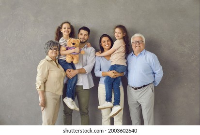 Studio Photo Shoot Group Portrait Of Cheerful Big Extended Multi Generational Family Against Grey Background.Happy Smiling Mom, Dad, Grandma, Grandpa And Two Little Kids All Together Looking At Camera