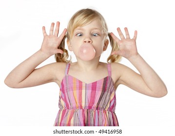 Studio Photo Of Small Female Child Blowing A Bubble With Gum. White Background.