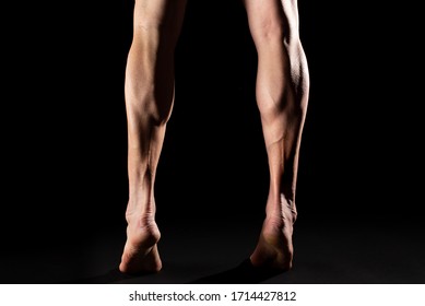 Studio photography of the legs and the calf muscle of a muscular cyclist athlete with black background