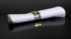 Studio Photography Of A White Serviette And Golden Serviette Ring In Dark Reflective Back