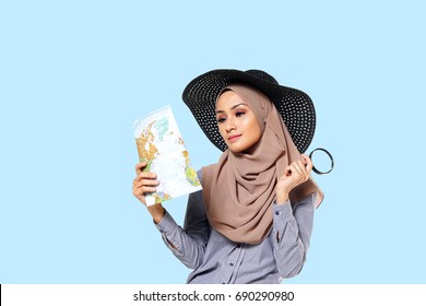 Studio Photography Of Young Happy Beautiful Asian Muslim Woman Smiling And Checks Map To Find Directions. Travel Concept.                      