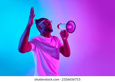 Studio photoshoot of african-american man shouting in megaphone and holding hands up to sky over colorful studio background in neon. Concept of human emotions, question, news, universe, sales, ad - Powered by Shutterstock