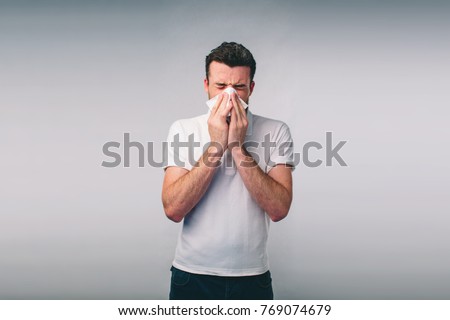 studio picture from a young man with handkerchief. Sick guy isolated has runny nose. man makes a cure for the common cold.Nerd is wearing glasses.