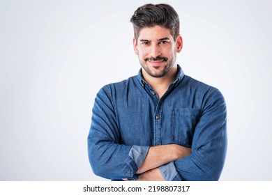 Studio portait of handsome standing with arms crossed. Copy space. Male is wearing denim shirt against white background. He is smiling.