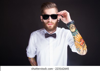 studio portarit of  ayoung fashionable hipster man in white shirt posing over a black background
