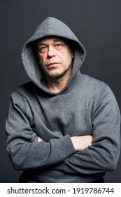 Studio Portrait Of A 40-50-year-old Serious Man In A Gray Hoodie On A Neutral Background, Looking At The Camera, Eyes Swollen. Maybe He's An Actor Or A Truck Driver, A Lawyer Or A Retired Military Man