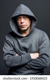 Studio Portrait Of A 40-50-year-old Serious Man In A Gray Hoodie On A Neutral Background, Looking At The Camera, Eyes Swollen. Maybe He's An Actor Or A Truck Driver, A Lawyer Or A Retired Military Man