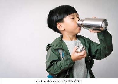 Studio portrait: Adorable little Asian boy drinks water from stainless steel reusable water bottle. Eco Friendly Lifestyle, Reduce Single Use Plastic, No Straw, Green Living, World Water Day.