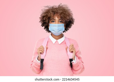 Studio Portrait Of African American School Girl Or College Student With Curly Afro Hair Wearing Medical Mask, Isolated On Pink Background