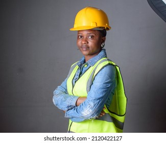 Studio portrait of an African Nigerian career lady or female engineer wearing a yellow safety helmet and a reflective jacket