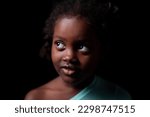 Studio portrait of an African-American girl of Ethiopian descent, looking away from the camera. Rembrandt lighting on black paper. 