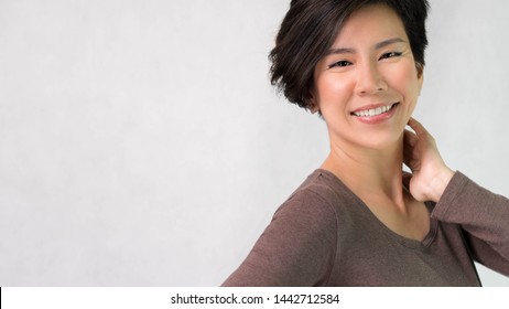 Studio Portrait Of An Attractive Smart Asian Middle Aged Woman Model In Her 40s Smiling Feeling Cheerful, Satisfied And Confident. Short Hair, Aging, Middle Aged Beauty And Healthy Concept. Banner.