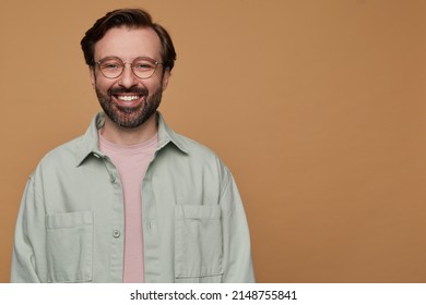 Studio Portrait Of Bearded Man Posing Over Beige Background Looking Into Camera With Broad Smile On His Face