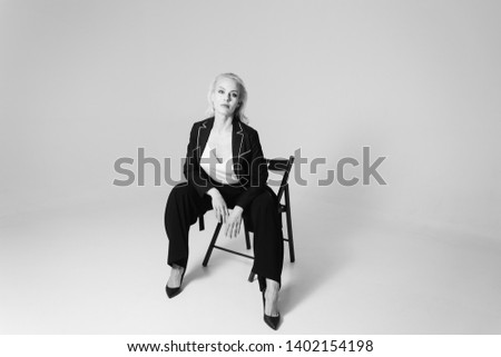 Studio portrait of beautiful blond woman in a black dress against white plain background