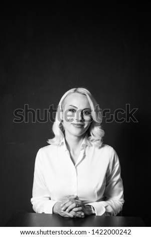 Studio portrait of a beautiful blonde woman in a white shirt against black plain background