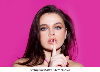 Studio Portrait Of Beautiful Elegant Woman. Young Lady Showing Shhh Taboo Sign With Finger To Lips Over Pink Background, Isolated.