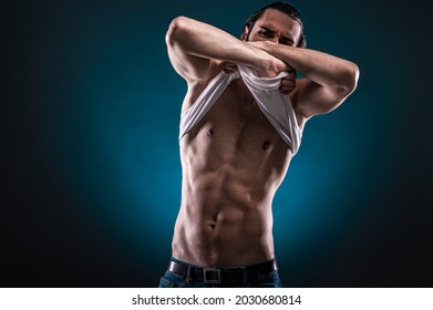 Studio portrait of a beautiful masculine bearded shirtless man showing his abdomen muscles