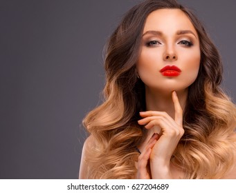 Studio Portrait of Beautiful Model with Volume Shiny Wavy Hair. Fashion Make Up and Curly Ombre Hair. Close up

