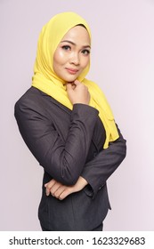 Studio Portrait Of A Beautiful Young Asian Muslim Businesswoman In A Black Suit And Yellow Hijab Isolated Over White Background. Corporate People Business Working Concept.