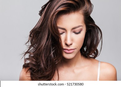 Studio portrait of a beautiful young woman with long brunette hair. Pretty spa model girl with perfect fresh clean skin. Youth and skin care concept
