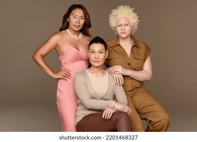 Studio portrait of a Black woman with albinism in her 20's, a Southeast Asian woman in her 30's, and a Japanese woman with alopecia in her 30's confidently looking at camera on a neutral background. Stock Photo