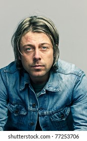 Studio Portrait Of Casual Young Man With Long Blond Hair Wearing Jeans Jacket Cool Looking.