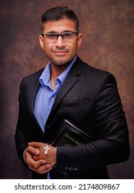 Studio Portrait Of Caucasian Christian Man With Glasses In Business Suit Holding Holy Bible With Jesus Cross