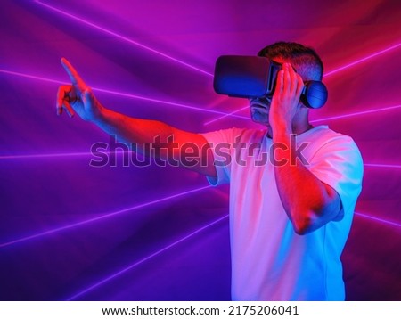 studio portrait of caucasian man using 3D virtual reality headset going into cyberspace playing video game with neon light background. Concept of virtual reality world of cysberspace and metaverse