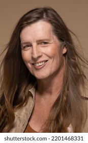 Studio Portrait Of A Caucasian Transgender Woman In Her 50's Smiling On A Neutral Background.