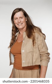 Studio Portrait Of A Caucasian Transgender Woman In Her 50's Smiling On A White Seamless.