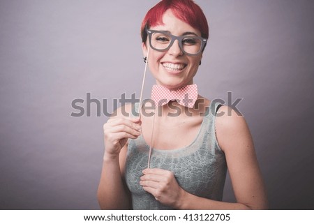 Studio portrait of confused young woman holding up spectacles in front of face