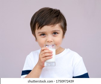 Studio Portrait Of Cute Toddler Drinking Fresh Milk From A Glass, Healthy Kid Boy Wearing White Shirt With Smiling Face And Holding Glass Of Milk, Healthy Drink For Children Concept
