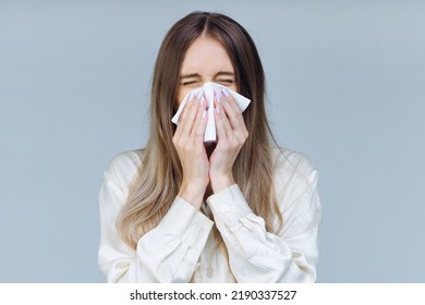 Studio Portrait Of Cute Unhealthy Caucasian Female With Paper Napkin Sneezing, Experiences Allergy Symptoms, Caught A Cold