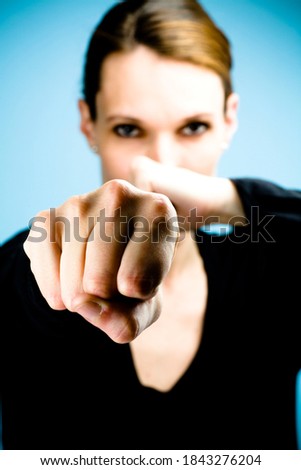 Studio portrait of a dark haired woman showing fists towards camera, selective focus - shallow depth of field.
