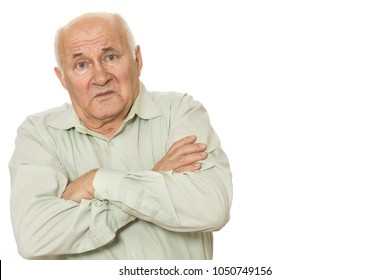 Studio portrait of a disappointed old man with his arms crossed. Senior man looking upset and unhappy posing isolated on white. Sad grandpa at studio.