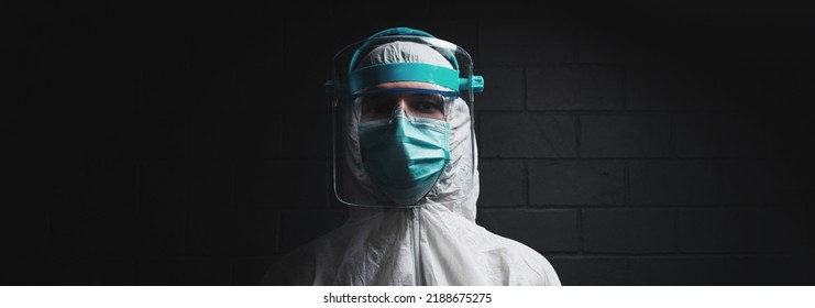 Studio Portrait Of A Doctor In Protective Suit On Black Background. Panoramic Banner View.