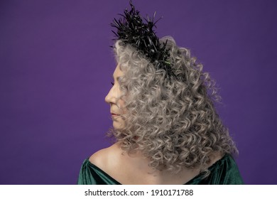 Studio Portrait Of An Elderly Woman 60-65 Years Old In A Beautiful Dress With A Crown On Her Head On A Colored Background. Concept: Stylish Pensioners Of Model Appearance, Active Life.