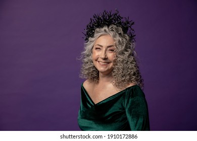 Studio Portrait Of An Elderly Woman 60-65 Years Old In A Beautiful Dress With A Crown On Her Head On A Colored Background. Concept: Stylish Pensioners Of Model Appearance, Active Life.