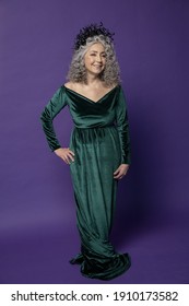 Studio Portrait Of An Elderly Woman 60-65 Years Old In A Beautiful Dress With A Crown On Her Head On A Colored Background. Concept: Stylish Pensioners Of Model Appearance, Active Life.