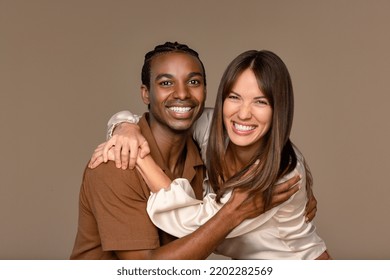 Studio Portrait Of An Eurasian Woman And A Black Man Both In Their 20s Embracing On A Neutral Background