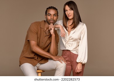 Studio Portrait Of An Eurasian Woman And A Black Man Both In Their 20s Posed Confidently On A Neutral Background