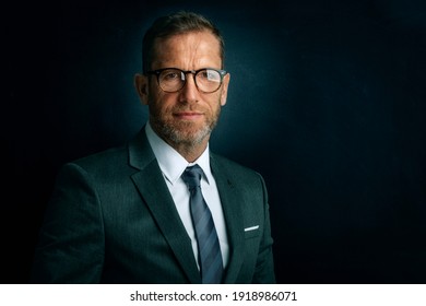 Studio portrait of executive businessman standing at isolated dark background. Copy space. 