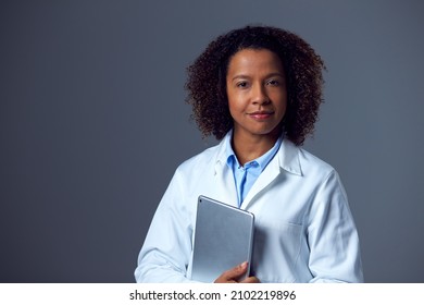 Studio Portrait Of Female Doctor In Lab Coat Holding Digital Tablet