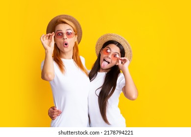 Studio Portrait Of Funny Child With Mum. Funny Face. Mom And Teenager Daughter Hugging Lovely Cuddling, Wearing White T-shirts Straw Hat And Sunglasses, Isolated On Bright Yellow Background.