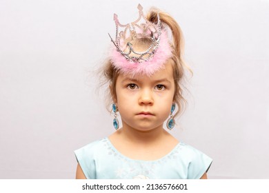 Studio Portrait Of A Girl In A Crown And Earrings On A Light Background. Concept: A Little Princess, A Young Fashionista, Children's Jewelry For Girls.