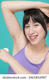 Studio portrait of girl smiling using deodorant