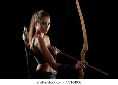 Studio portrait of a gorgeous young long haired female warrior looking to the camera holding a bow posing on black background copyspace archer archery medieval character Amazon tribe.