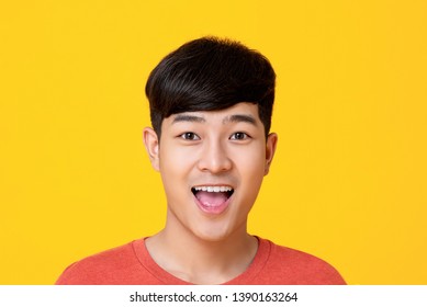 Studio Portrait Of  Handsome Young Asian Man Face Smiling With Mouth Open Isolated On Colorful Yellow Background