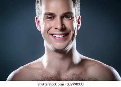 Studio Portrait Of Handsome Young Man. Clean Shaven Man With Naked Torso Looking At Camera And Smiling