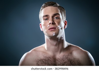 Studio Portrait Of Handsome Young Man. Clean Shaven Man With Naked Torso Looking At Camera. His Face With Cuts After Shaving